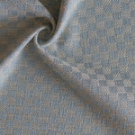 Close up of draped woven fabric with small scale checkerboard pattern in white and pastel blue.