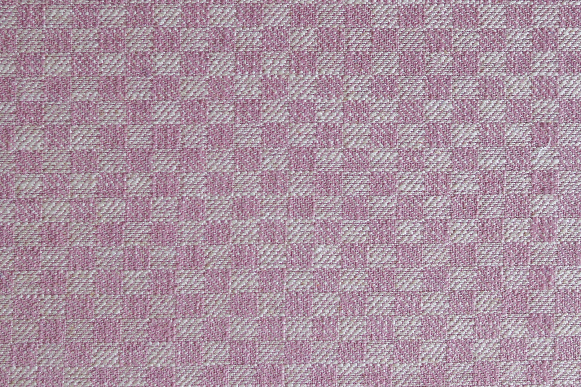 Close up of woven fabric with small scale checkerboard pattern in white and bubble gum pink.