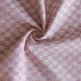 Close up of draped woven fabric with small scale checkerboard pattern in white and bubble gum pink.