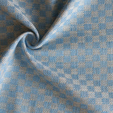 Close up of draped woven fabric with small scale checkerboard pattern in white and sky blue. 