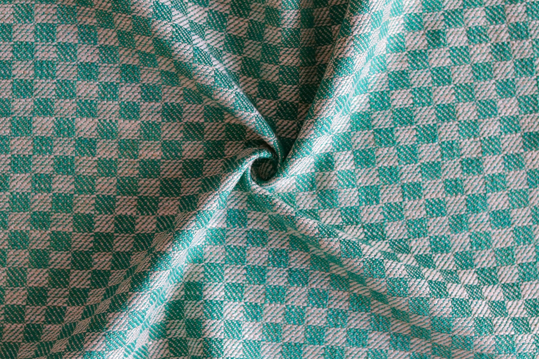 Close up of draped woven fabric with small scale checkerboard pattern in white and teal blue. 