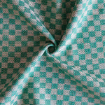 Close up of draped woven fabric with small scale checkerboard pattern in white and teal blue. 