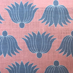 Detail of fabric in a repeating lotus print in blue and white on a coral field.