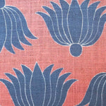 Detail of fabric in a repeating lotus print in blue and white on a coral field.