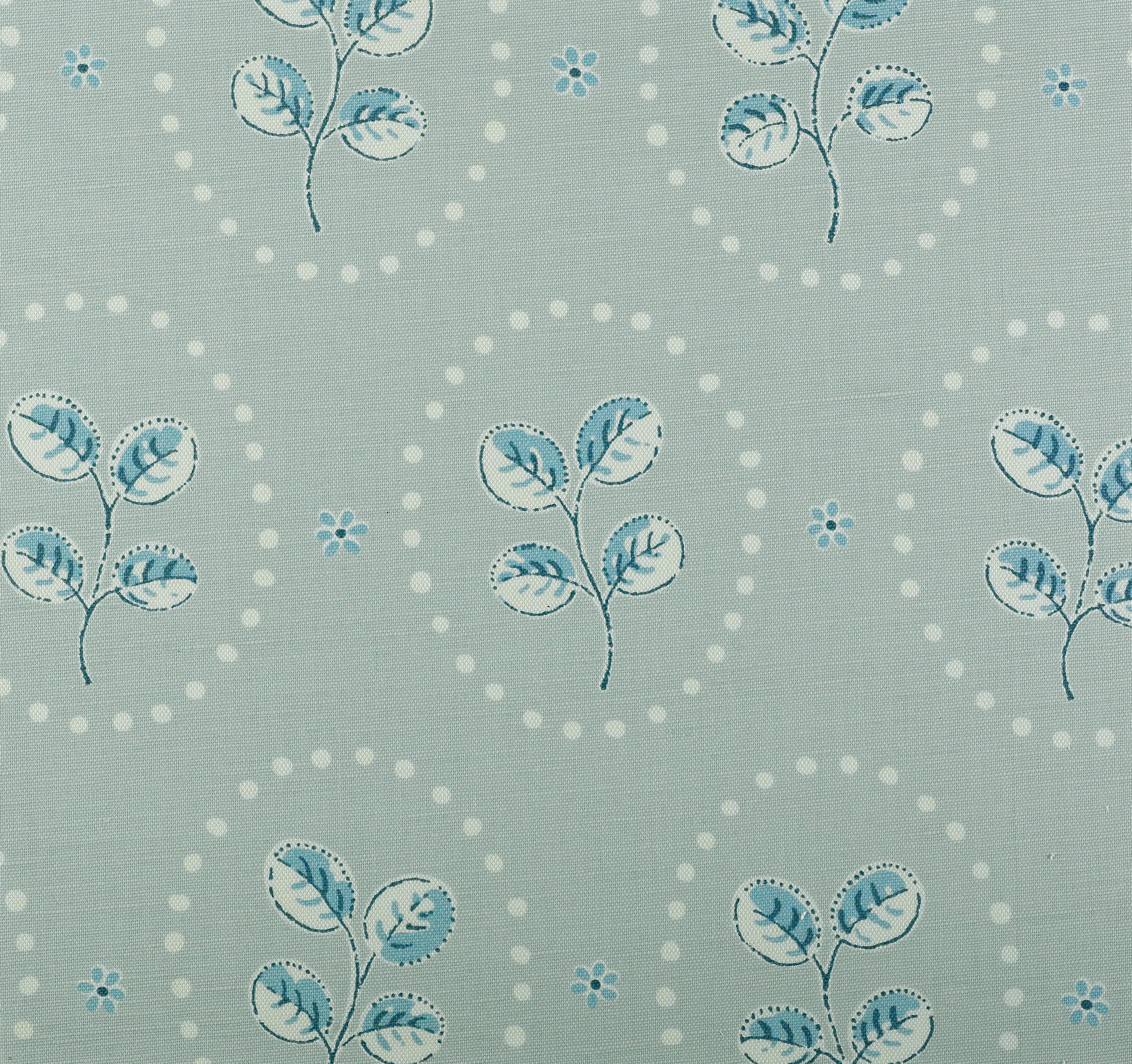 Detail of fabric in a repeating leaf print in blue and cream on a light blue field.