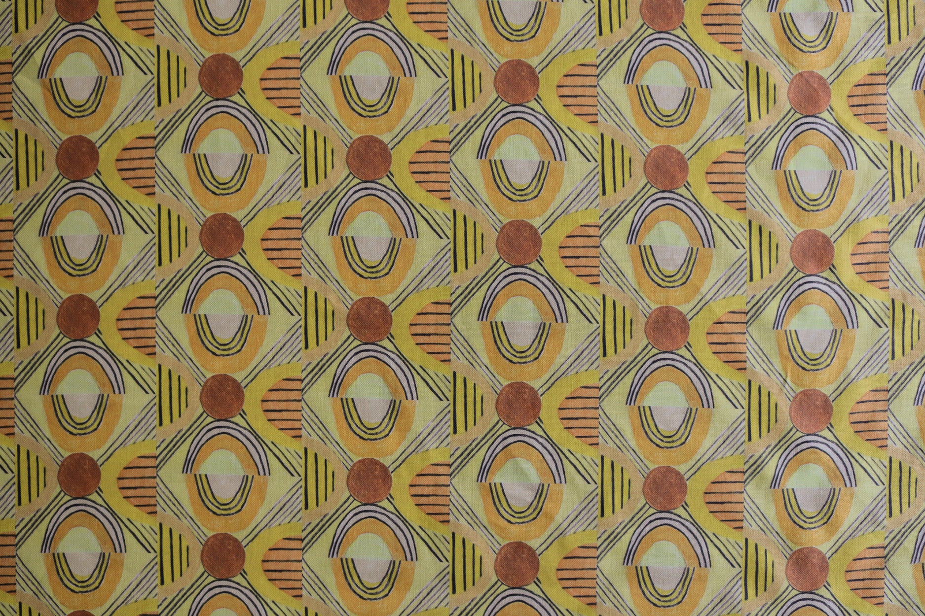 Printed fabric with a hand drawn geometric pattern in in yellow, orange and rust red and navy blue accent stripes. 