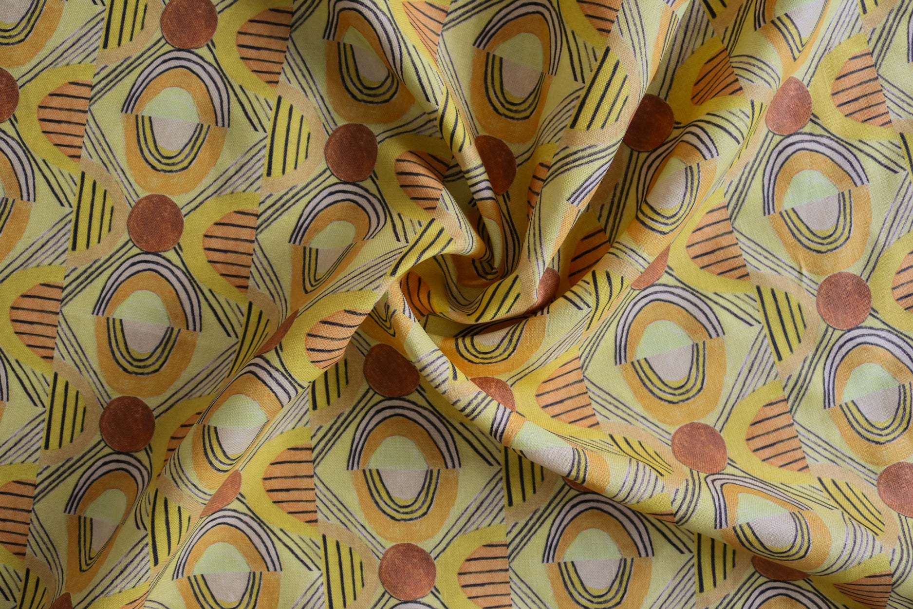 Close up of gently draped printed fabric with a hand drawn geometric pattern in in yellow, orange and rust red and navy blue accent stripes. 