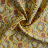 Close up of gently draped printed fabric with a hand drawn geometric pattern in in yellow, orange and rust red and navy blue accent stripes. 