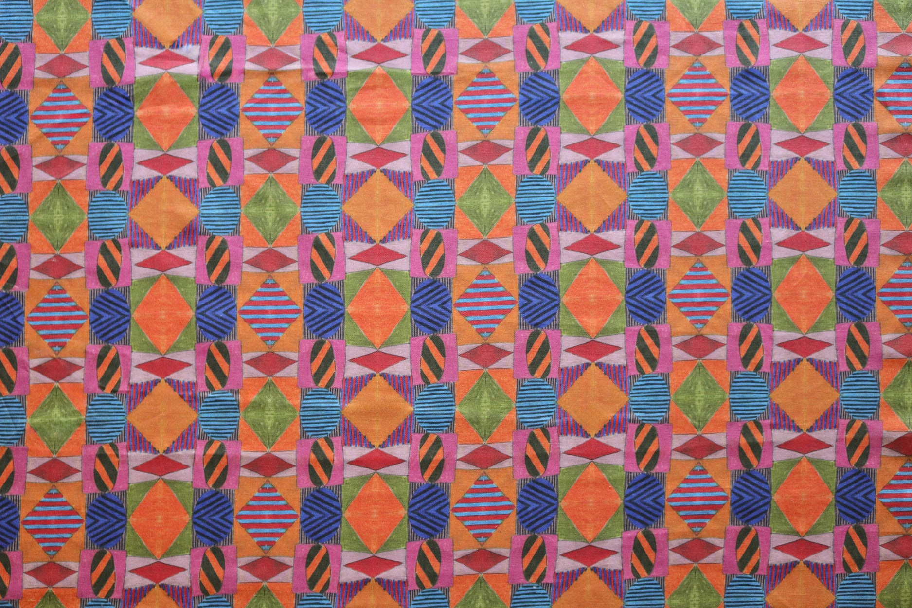 Close up of printed fabric with collaged pattern with striped and solid diamonds, squares and ovals in orange, red, pink, blue and green. 