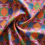 A close-up of draped fabric with a bold geometric pattern in orange, pink, blue, green and red.