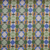 Close up of printed fabric with collaged pattern with striped and solid diamonds, squares and ovals in blue, green, orange and white. 
