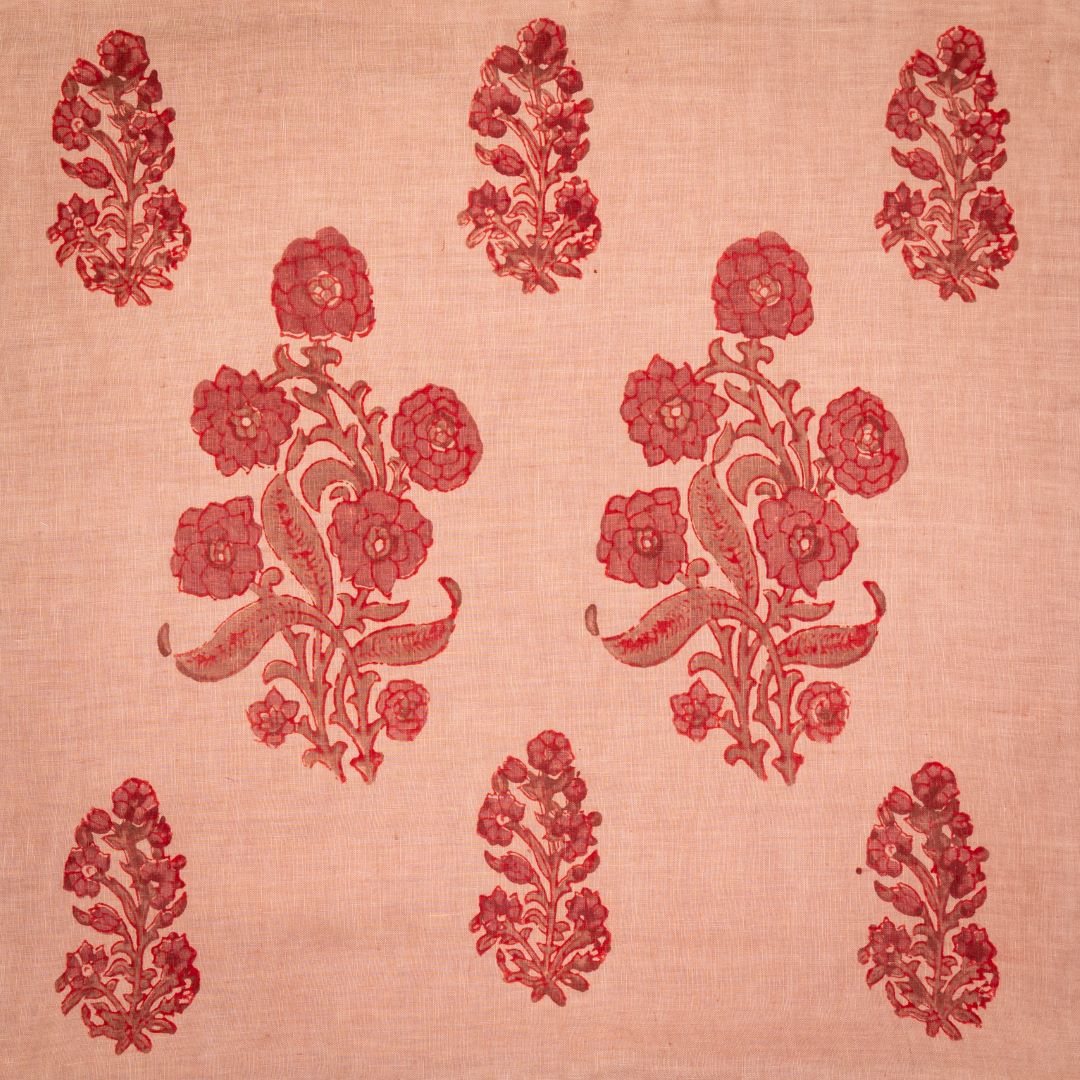 Detail of fabric in a floral grid print in red and maroon on a light orange field.