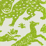 Detail of wallpaper in a playful animal print in green on a cream field.