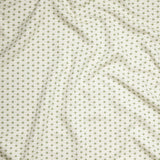 Close up of gently draped woven Indoor-Outdoor fabric with small scale geometric ditsy print in green and tan on white. 