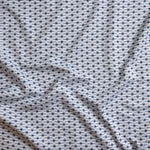 Close up of gently draped woven Indoor-Outdoor fabric with small scale geometric ditsy print in navy and slate blue on white. 
