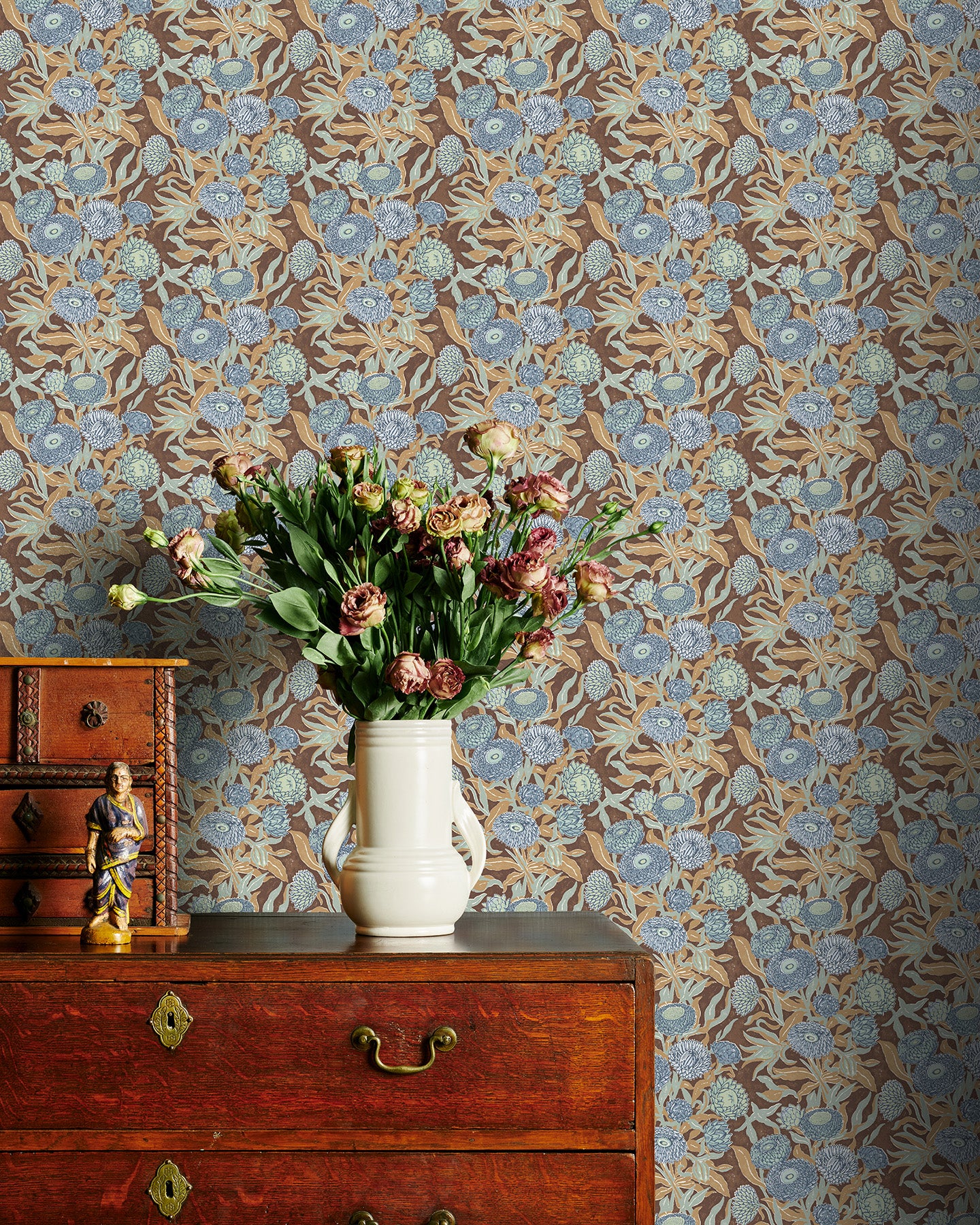 Blue and Brown floral wallpaper with a vase of flowers on a wooden dresser