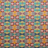 Close up of printed fabric with a complex geometric pattern with pink, red, blue, yellow, orange and turquoise.