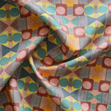 Close up of gently draped printed fabric with a complex geometric pattern with pink, red, blue, yellow, orange and turquoise
