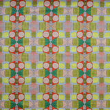 Close up of printed fabric with a complex geometric pattern with pink, red, light purple, green and yellow. 