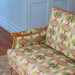 Detail of a wooden settee with bold geometric patterned upholstery on a Persian rug against a blue paneled wall . 