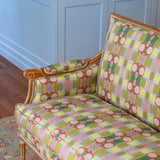 Detail of a wooden settee with bold geometric patterned upholstery on a Persian rug against a blue paneled wall . 