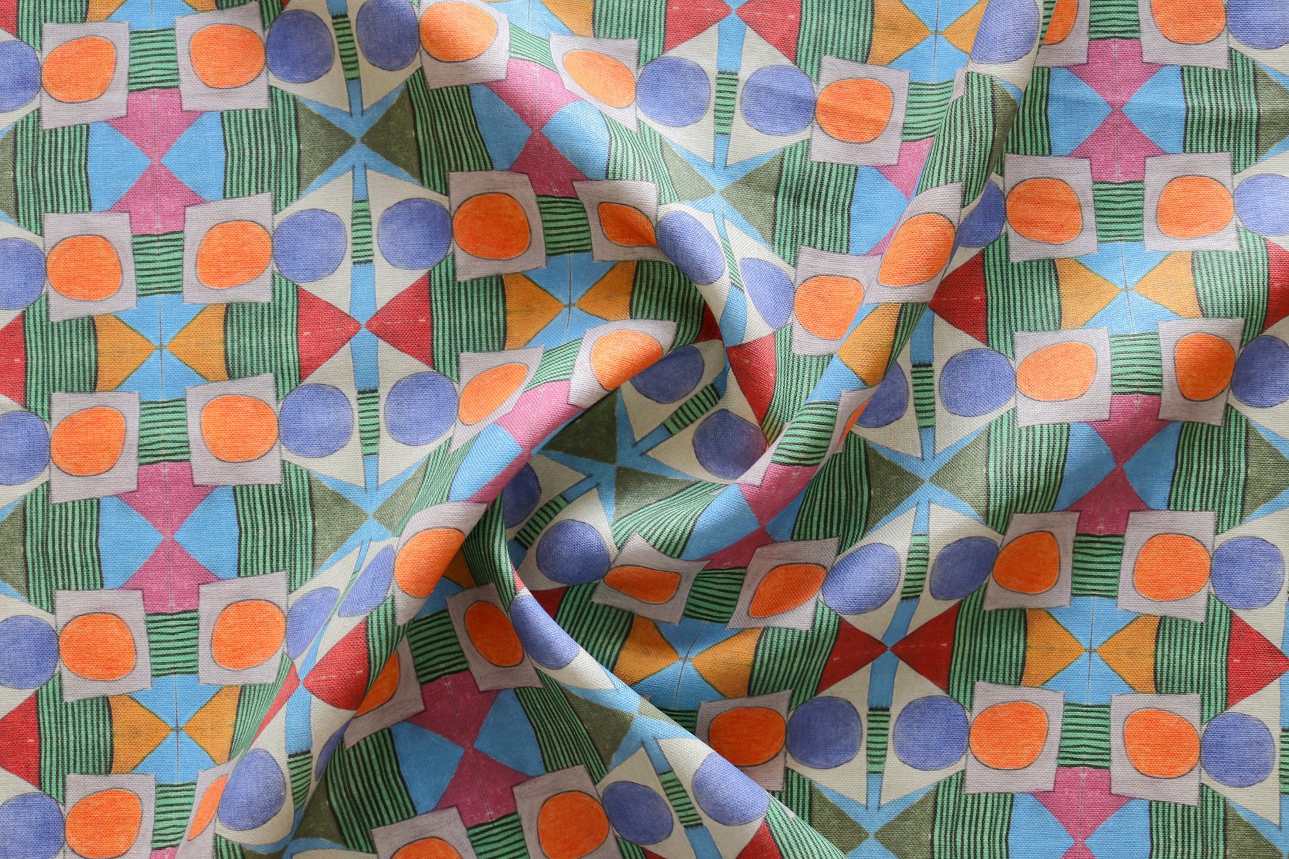 Close up of gently draped printed fabric with a complex geometric pattern with blue, orange, green, pink and red. 