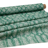 Draped fabric coming off a roll with monochomatic geometric stripe and mottled textural background in shades of green.