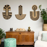 Living room scene with three black and tan sculptural woven panels, ornately carved wooden chest, baskets with house plans, white upholstered side chair and a stripe patterned footstool in green.