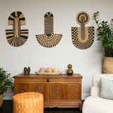 Living room scene with three black and tan sculptural woven panels, ornately carved wooden chest, baskets with house plans, white upholstered side chair and a stripe patterned footstool in orange.