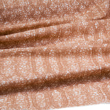 Draped fabric coming off a roll with monochomatic geometric stripe and mottled textural background in shades of  orange.