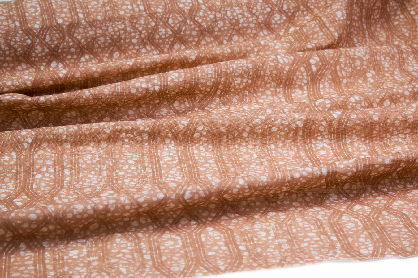 Draped fabric coming off a roll with monochomatic geometric stripe and mottled textural background in shades of  orange.
