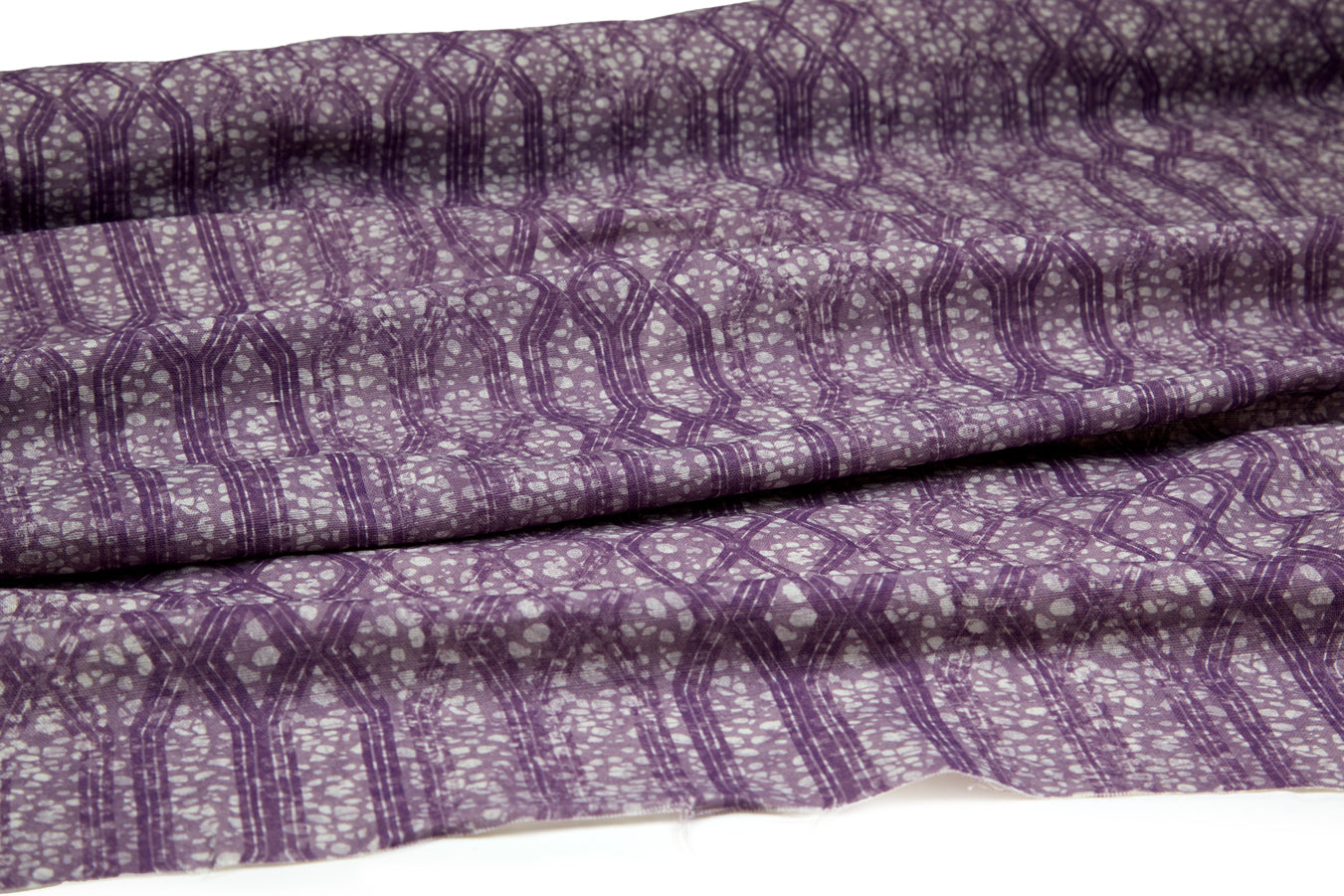 Draped fabric coming off a roll with monochomatic geometric stripe and mottled textural background in shades of purple.