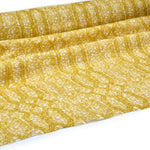 Draped fabric coming off a roll with monochomatic geometric stripe and mottled textural background in shades of yellow.
