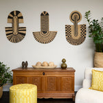 Living room scene with three black and tan sculptural woven panels, ornately carved wooden chest, baskets with house plans, white upholstered side chair and a stripe patterned footstool in yellow.