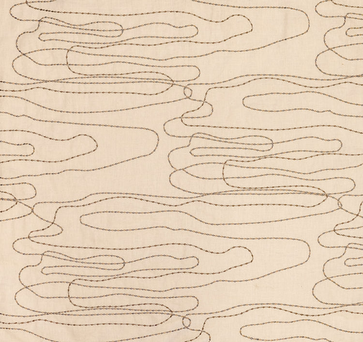 Detail of fabric in an abstract embroidered pattern in tan on a cream field.