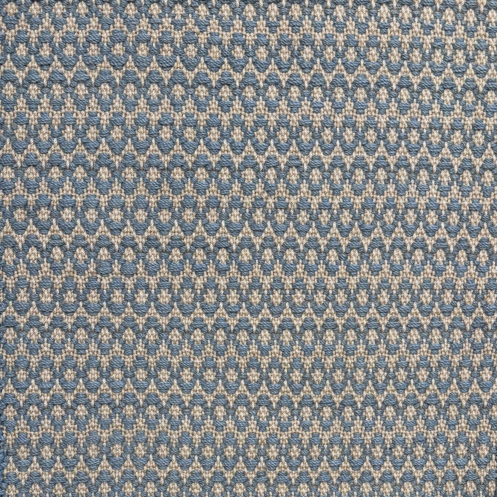 Handwoven wool with textural oval pattern in blue on a beige field. 