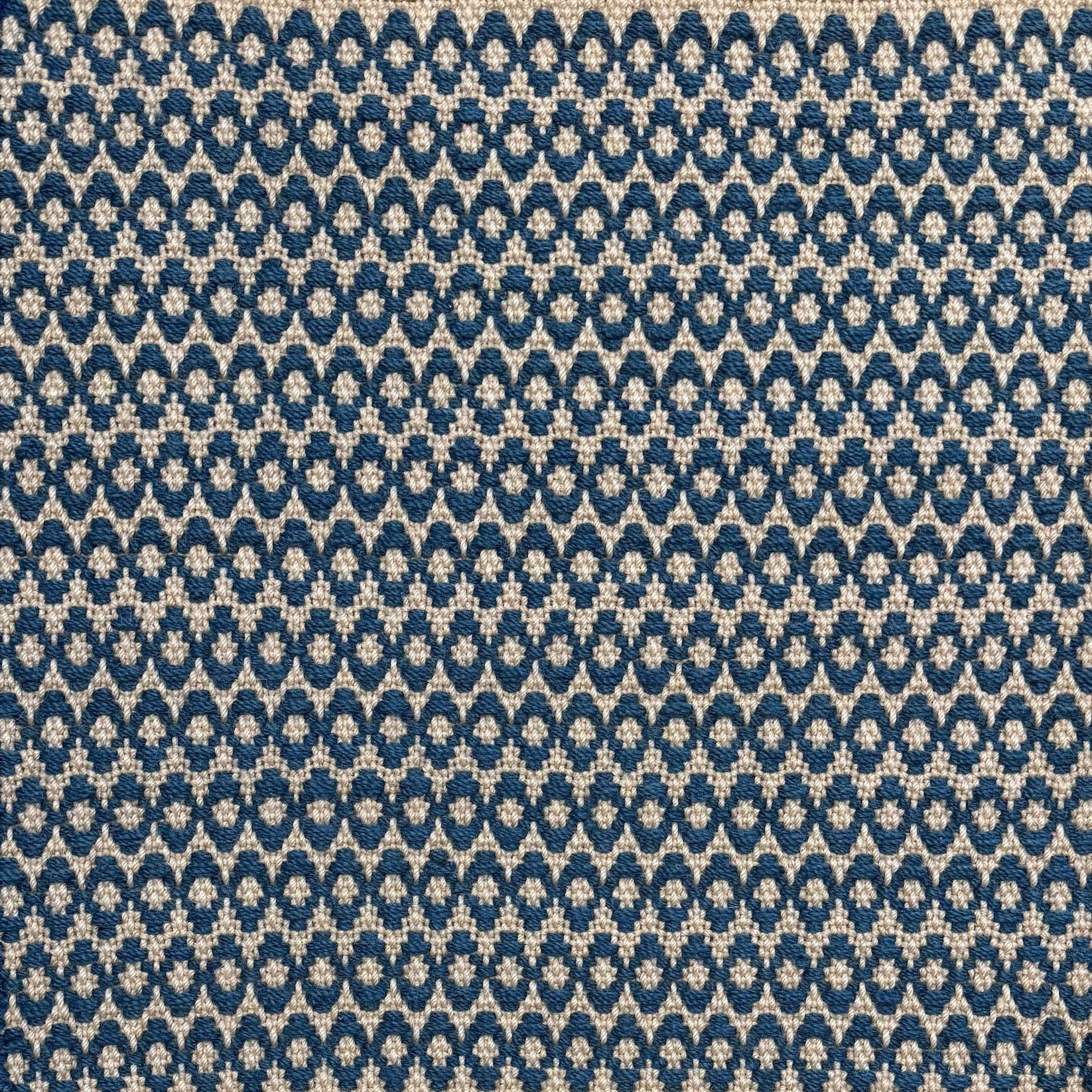 Handwoven wool rug with textural oval pattern in marine blue on a beige field. 