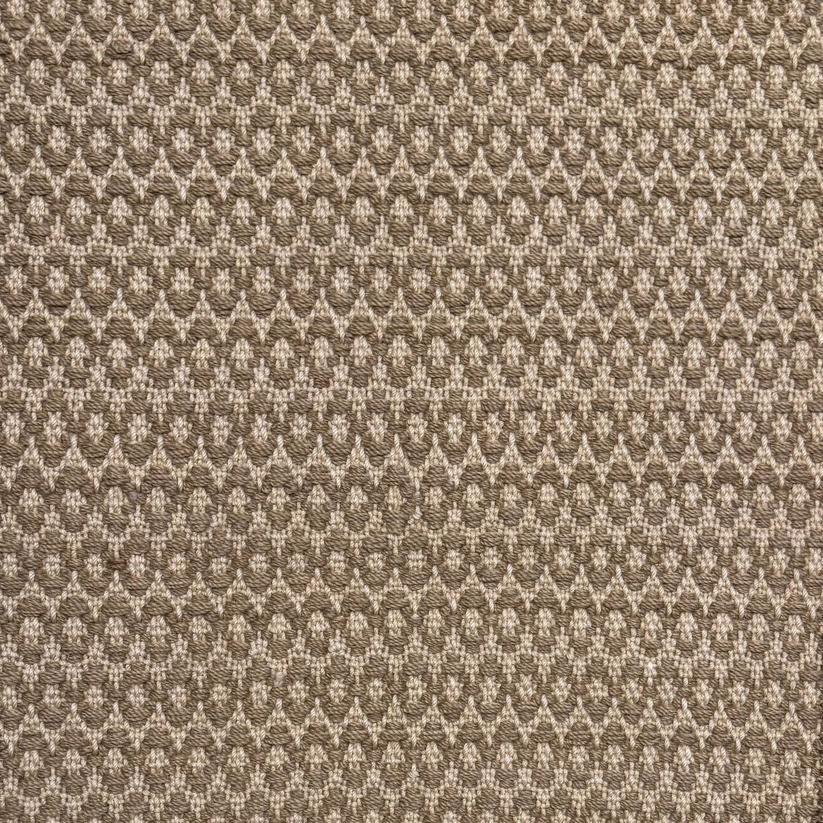 Handwoven wool rug with textural oval pattern in taupe on a beige field. 