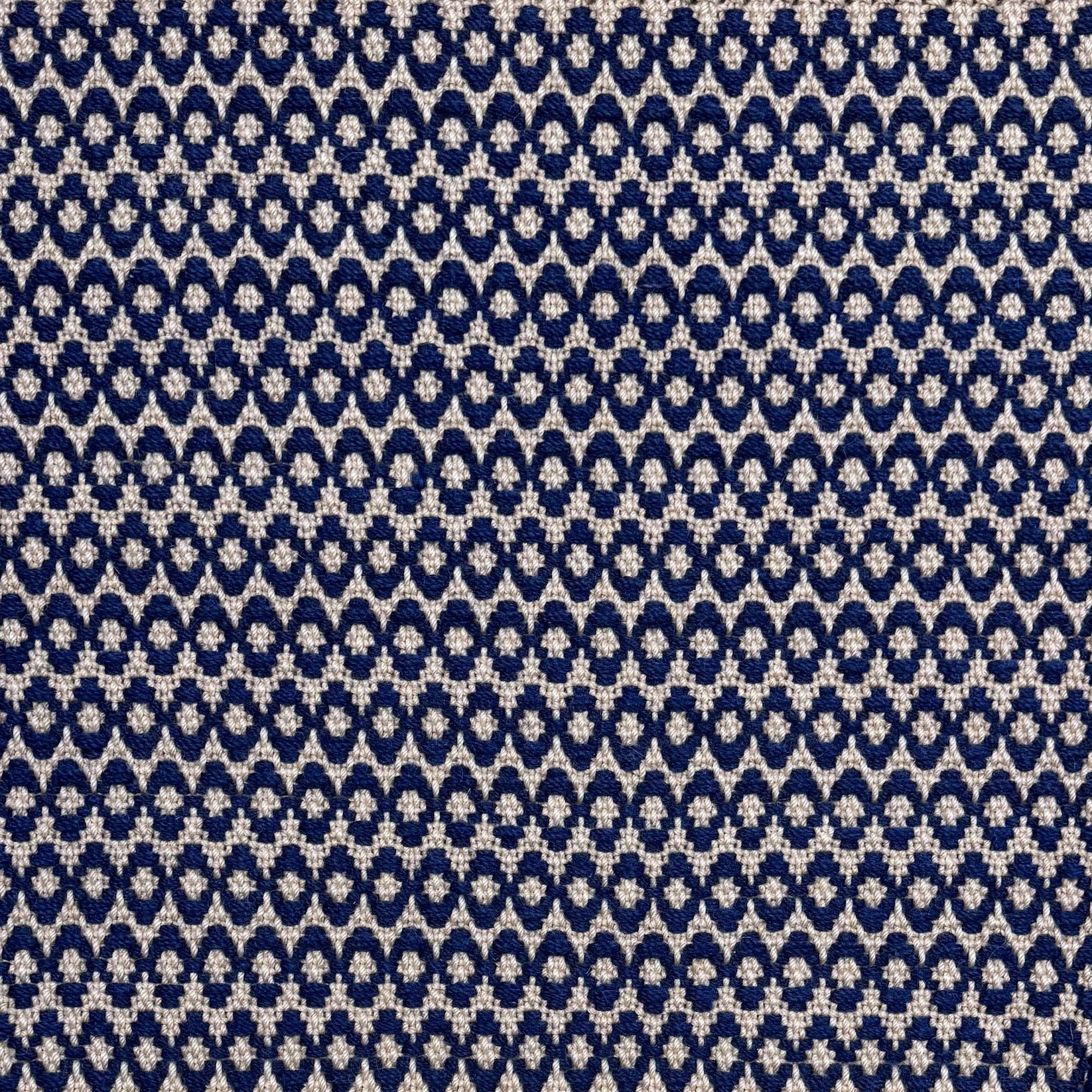 Handwoven wool rug with textural oval pattern in dark blue on a beige field. 