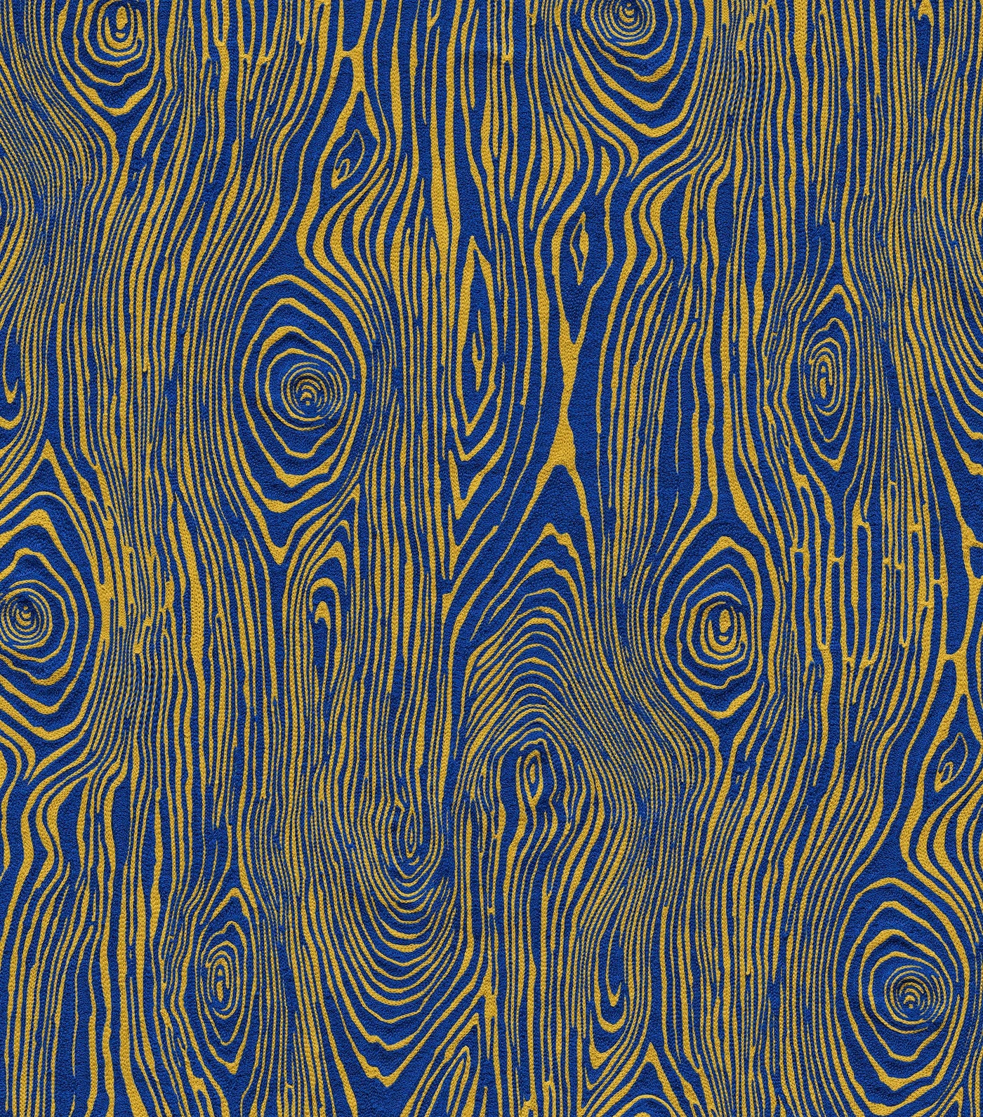 Detail of fabric in a textural wood grain print in yellow on a blue field.