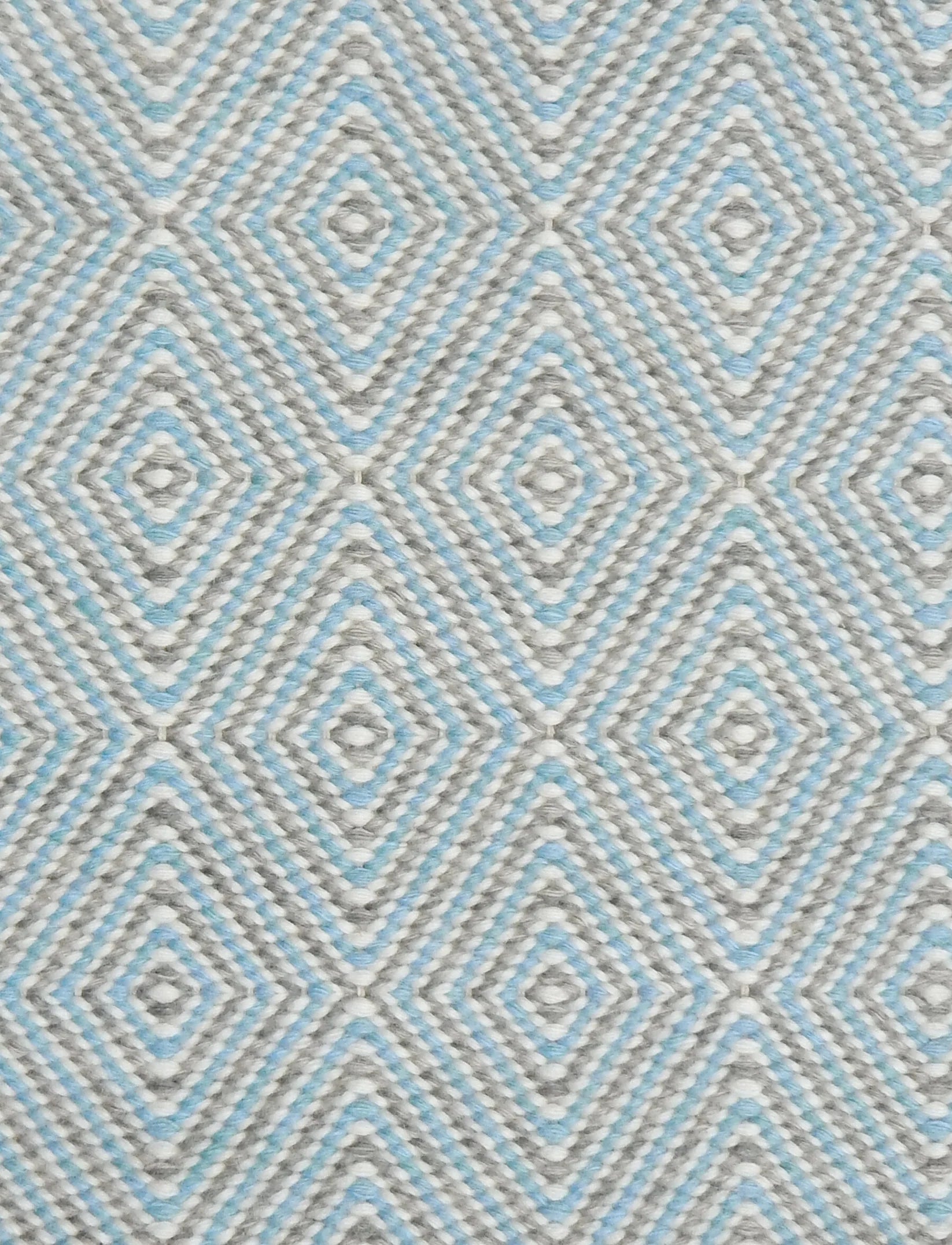 Handwoven rug in a geometric diamond pattern in light blue, grey and white. 