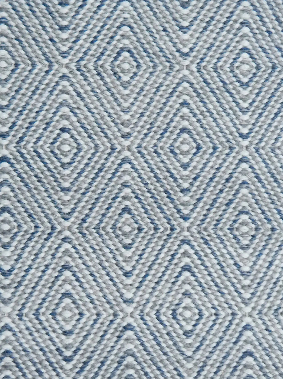 Handwoven rug in a geometric diamond pattern in blue, grey and white. 