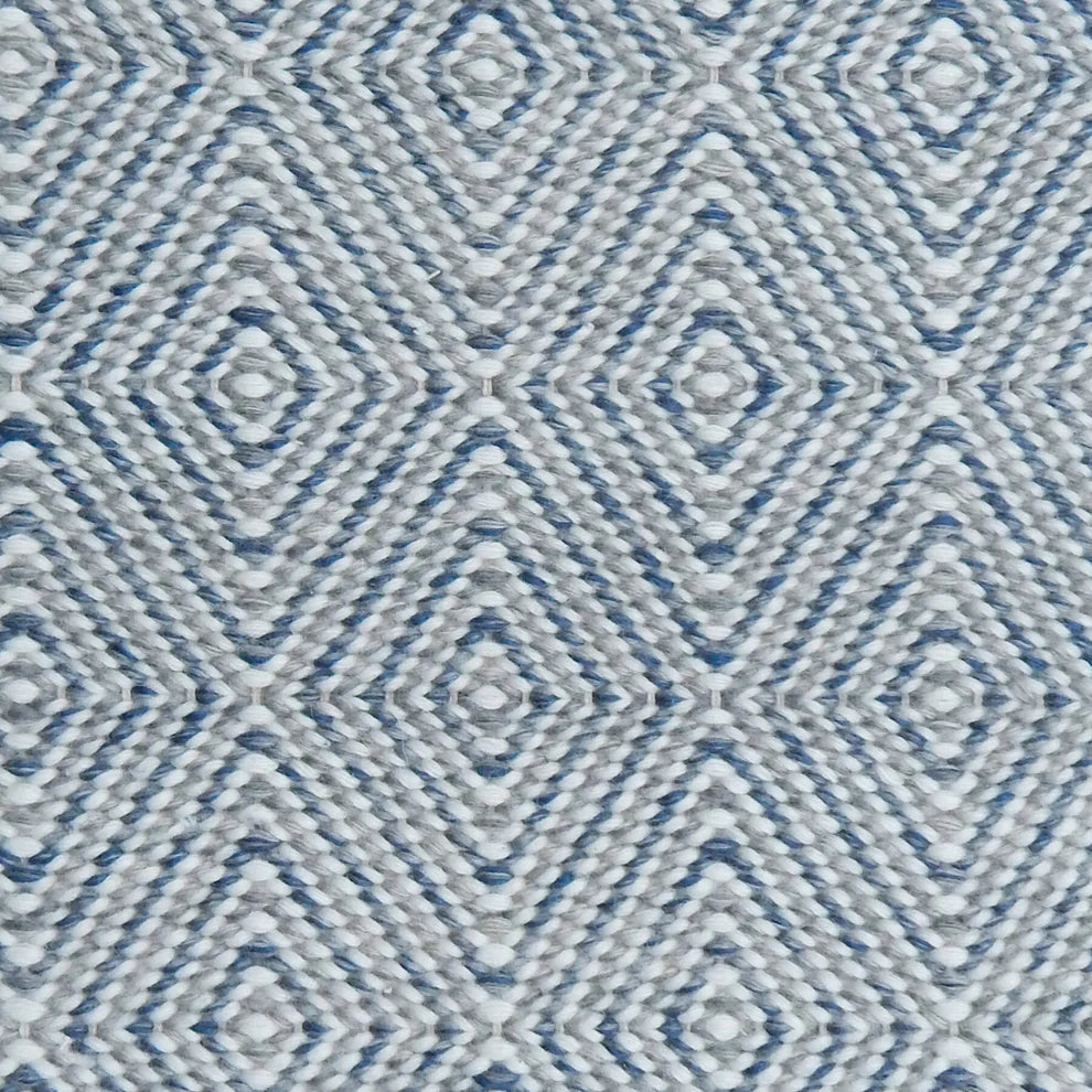 Handwoven rug in a geometric diamond pattern in blue, grey and white. 