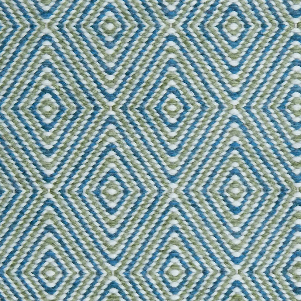 Handwoven rug in a geometric diamond pattern in blue, green and white. 