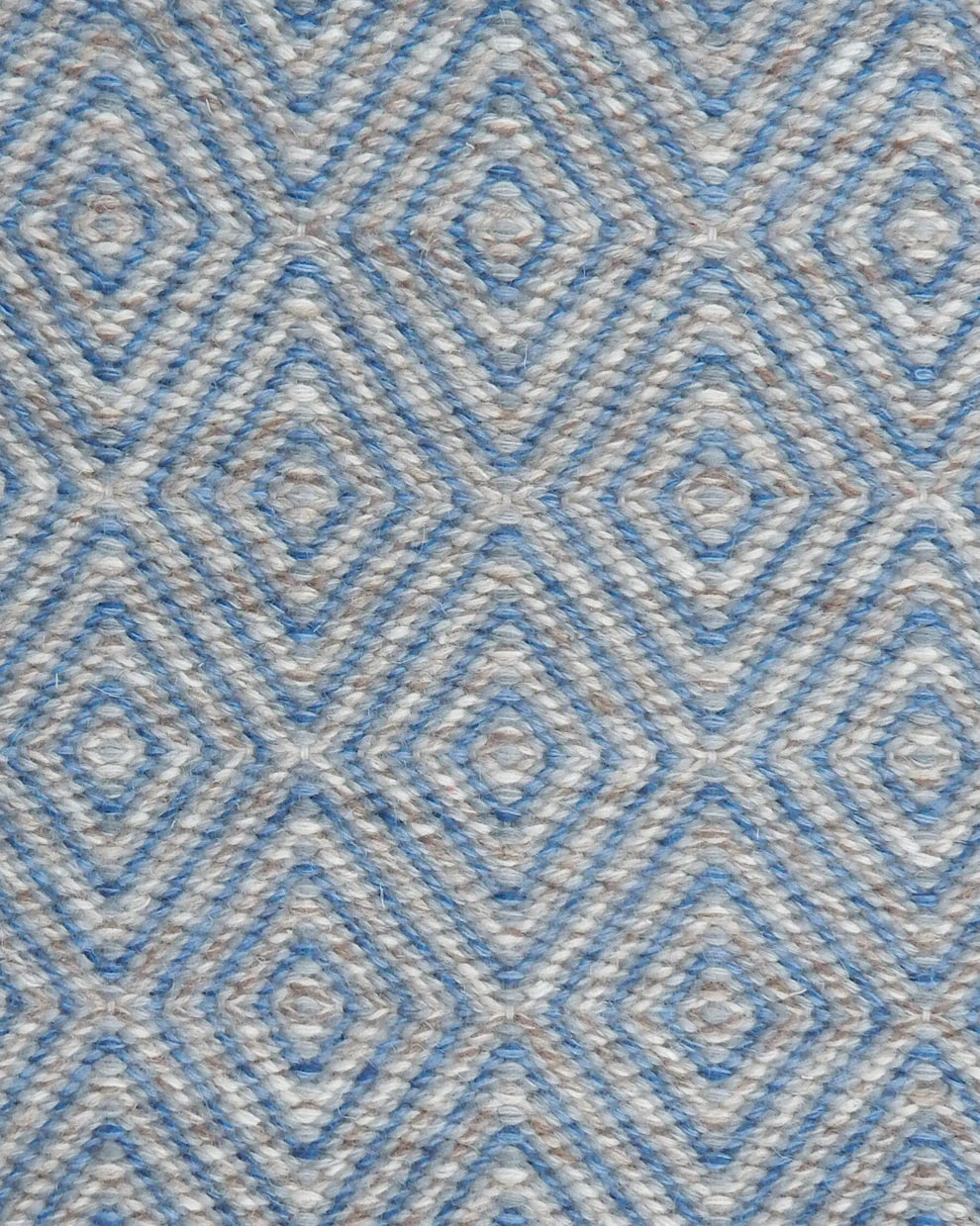 Handwoven rug in a geometric diamond pattern in blue and grey. 