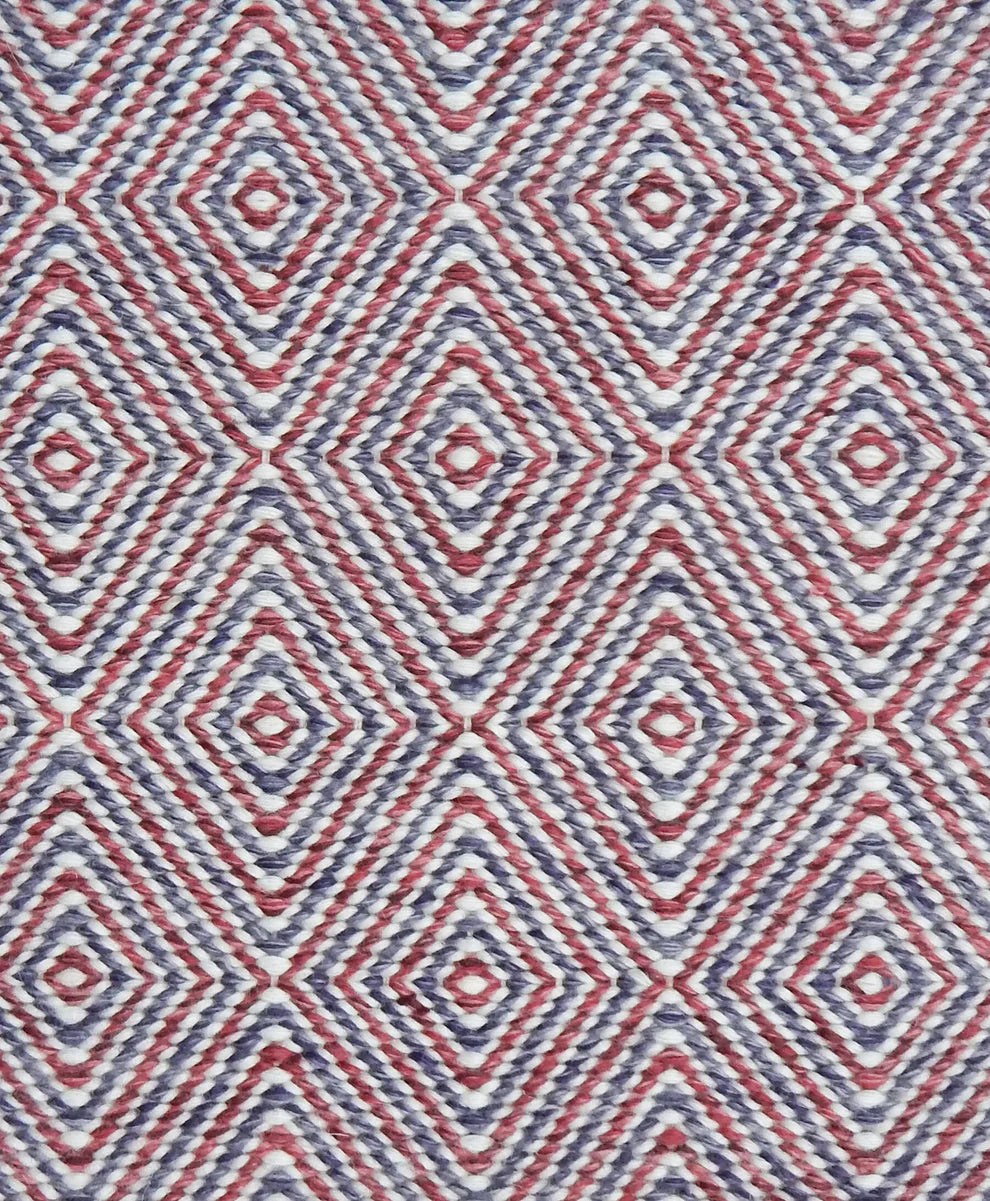 Handwoven rug in a geometric diamond pattern in red and purple. 