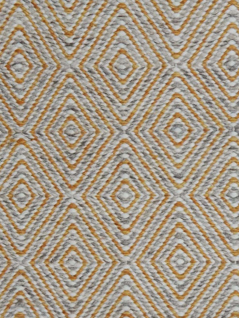Handwoven rug in a geometric diamond pattern in grey, yellow and white. 
