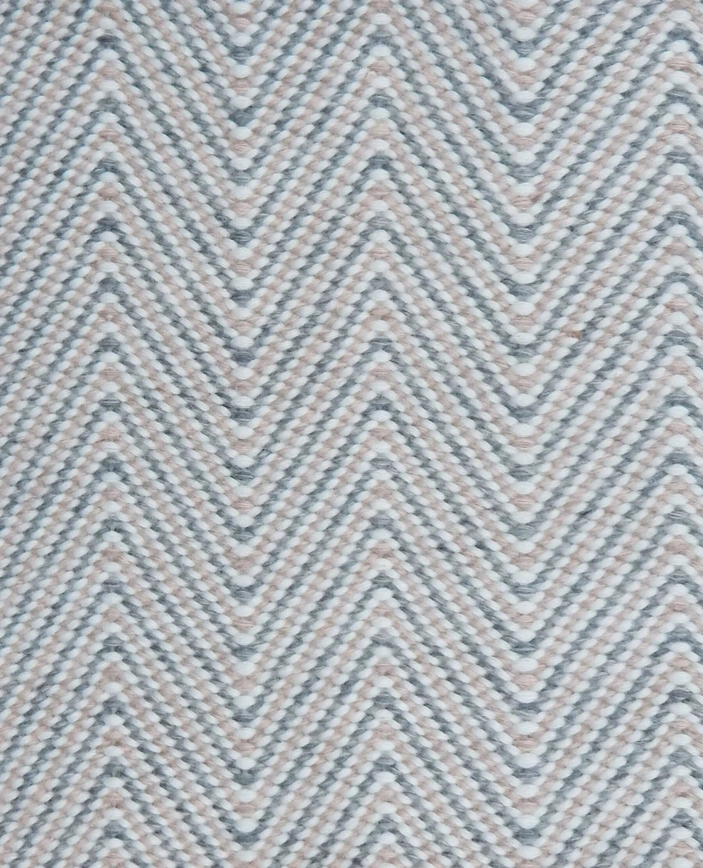 Handwoven rug in a herringbone pattern in pink, grey and white. 