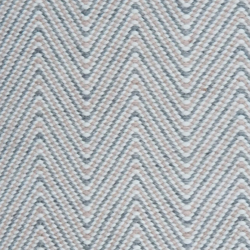 Handwoven rug in a herringbone pattern in pink, grey and white. 