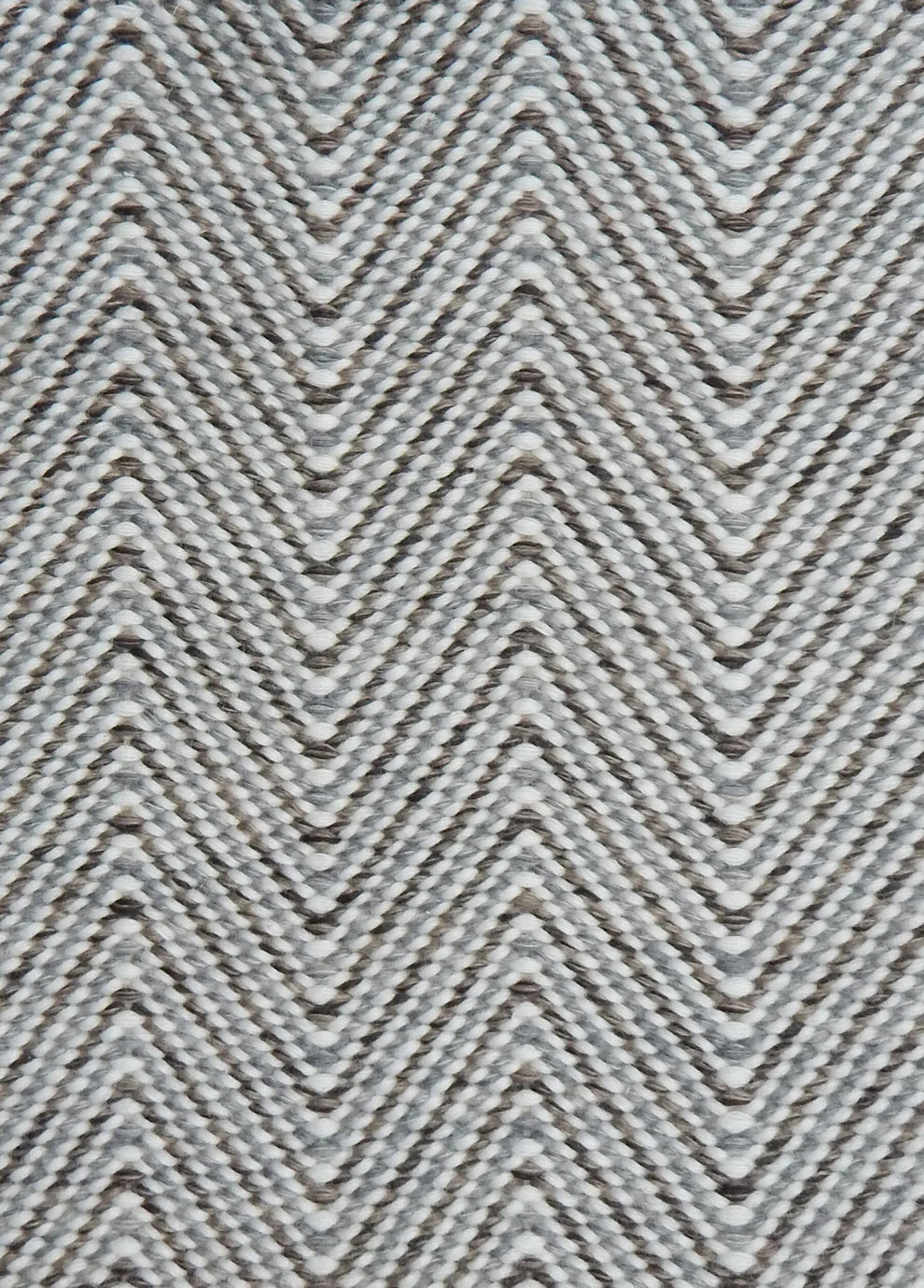 Handwoven rug in a herringbone pattern in shades of grey and white. 
